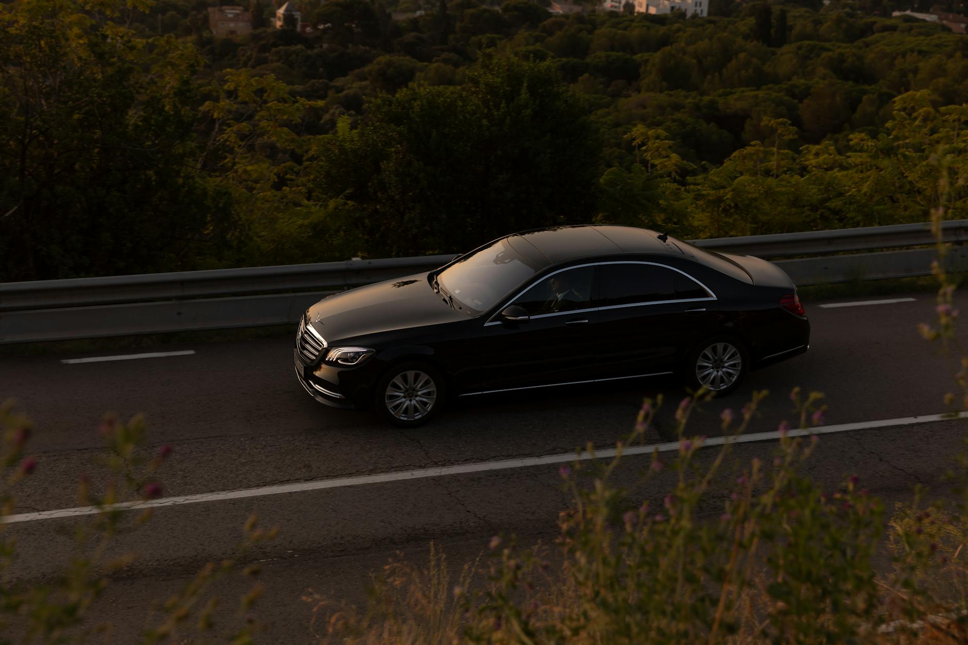 Jaguar XJ z drugiej ręki – luksusowa limuzyna czy ryzykowna zachcianka dla odważnych Czarny luksusowy sedan jedzie leśną drogą za dnia