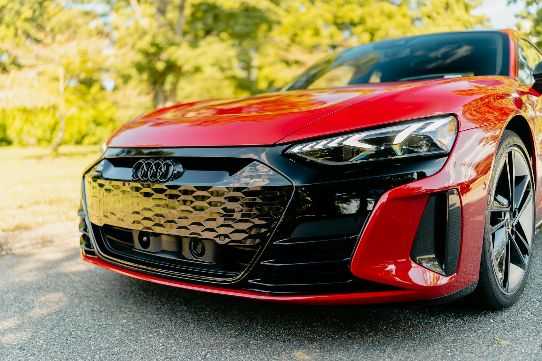 Zbliżenie czerwonego luksusowego auta elektrycznego w słońcu