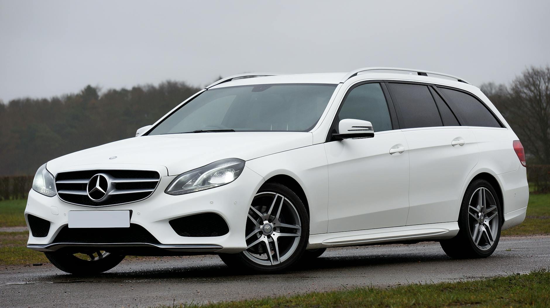 Białe kombi Mercedes E‑Class zaparkowane na tle pochmurnego nieba