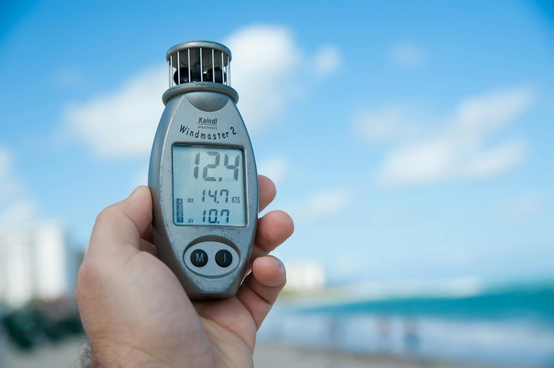 Dłoń trzymająca anemometr na tle nieba i plaży