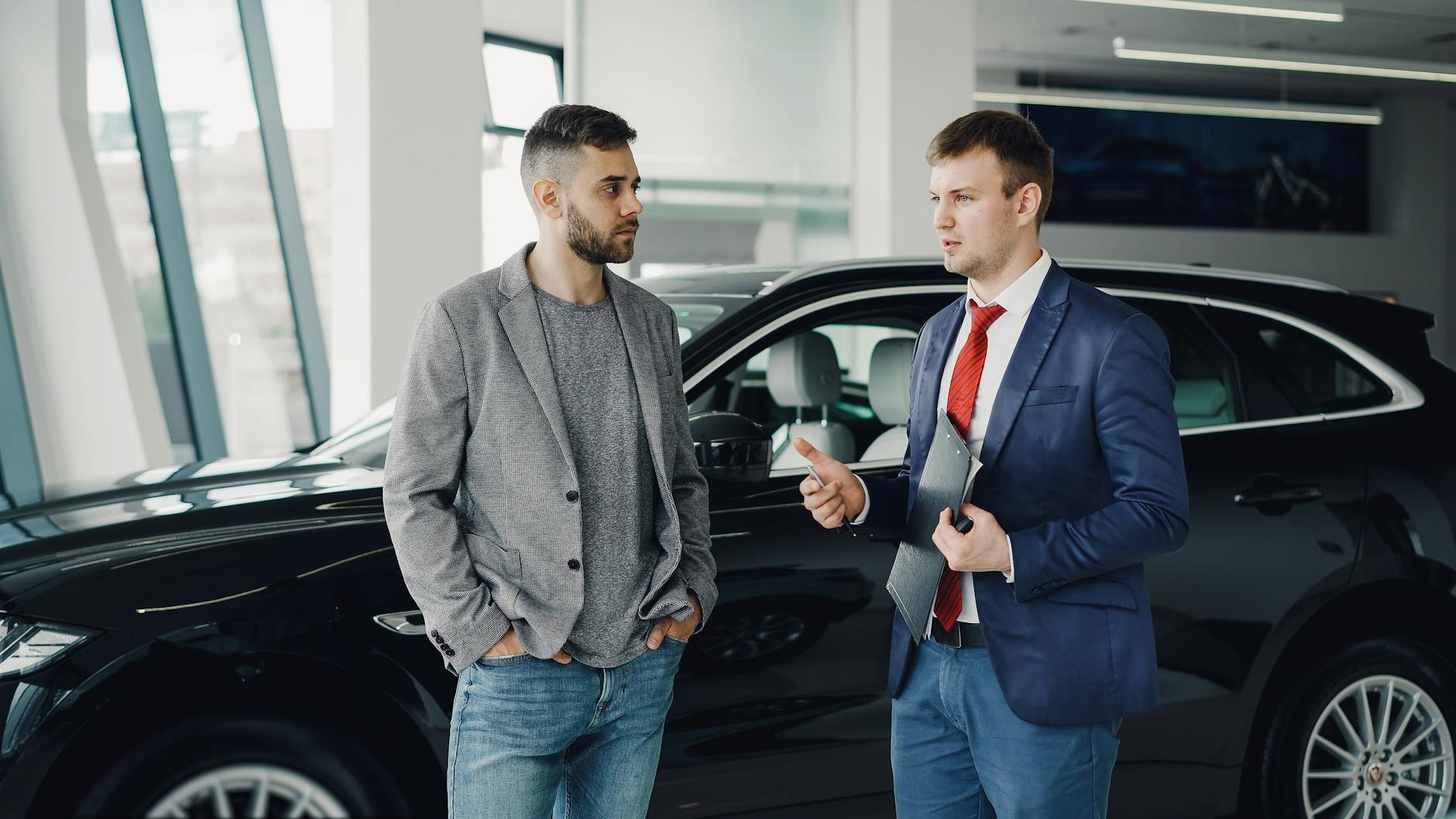 Dwóch mężczyzn rozmawia o ofercie ubezpieczenia auta w salonie premium