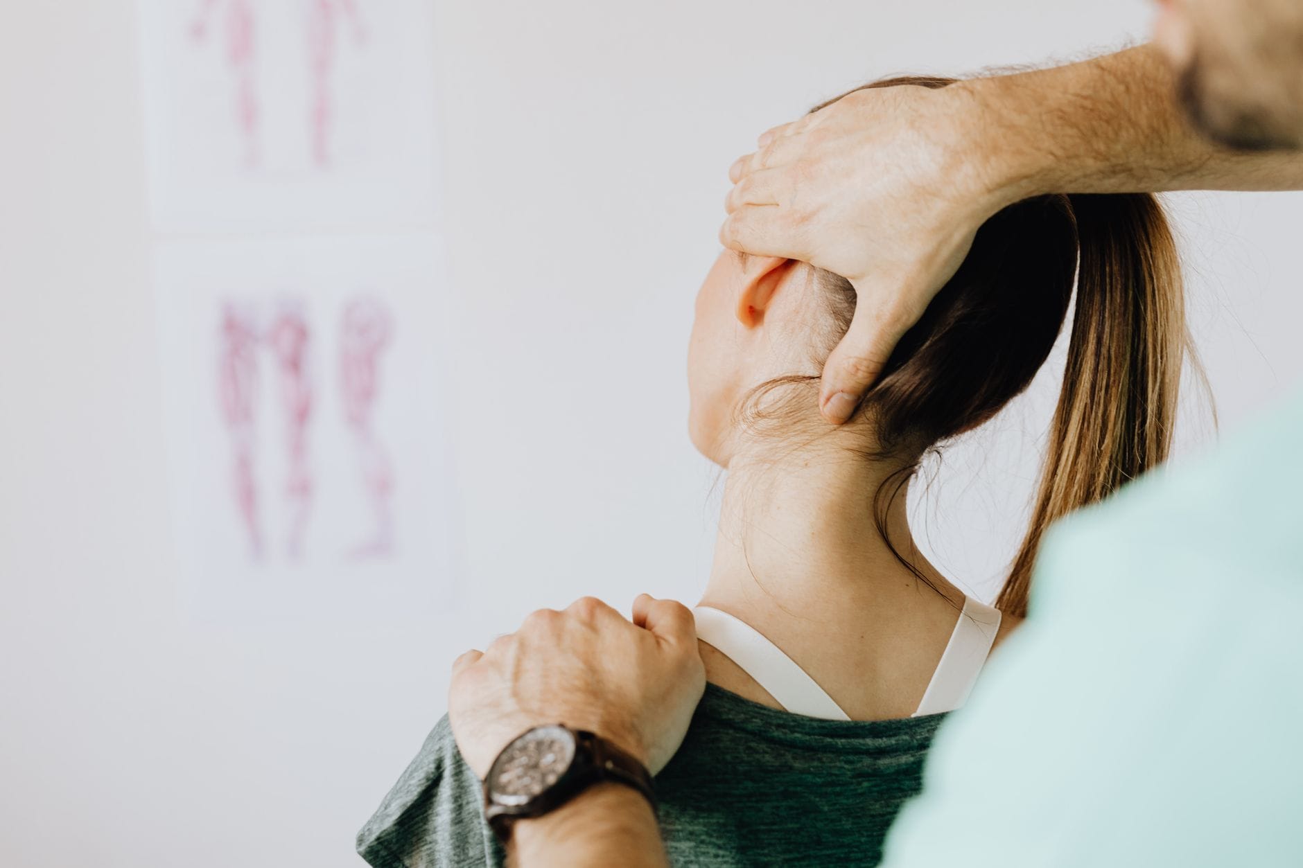 Fizjoterapeuta bada szyję pacjentki na tle rysunków anatomii